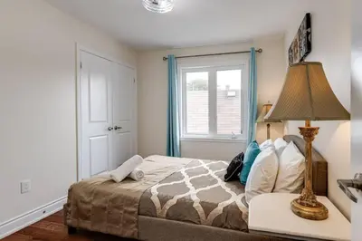 a bedroom with a bed with a lamp on a table at 3BR Casa close to Woodbine Beach with deck area and WFH in Toronto