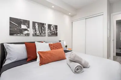 a bedroom with a white bed with orange and white pillows at Luxury CN Tower View King Bed Balcony FREE PARK in Toronto