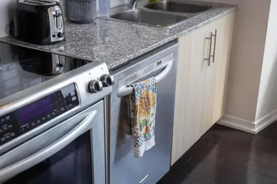 a kitchen with a stainless steel dishwasher and a sink at Skyline Waterfront 2BR plus 2BA wParking near MTCC in Toronto