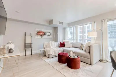 a white living room with a couch and a table at Stunning 1BR and Den Sleeps 6 Steps From CN Tower in Toronto