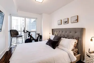 a bedroom with a large bed and a chair at 3BR Rooftop Pool Gym Steps to MTCC and CN Tower with Parking in Toronto