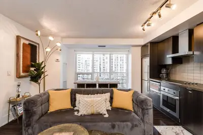 a living room with a couch and a kitchen at 3BR Rooftop Pool Gym Steps to MTCC and CN Tower with Parking in Toronto