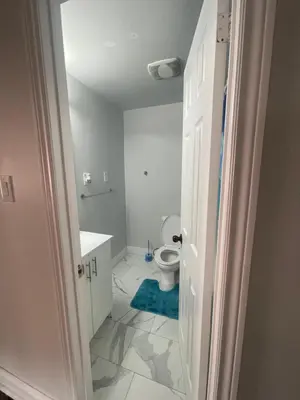 a bathroom with a toilet and a blue rug at Triple M Lodge Double in Mississauga