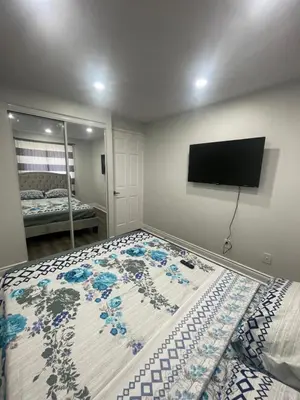 a bedroom with a bed with a television on the wall at Triple M Lodge Double in Mississauga