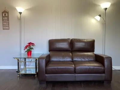 a brown leather couch in a living room with a table at Lucky home- Vacation Houses in Trenton