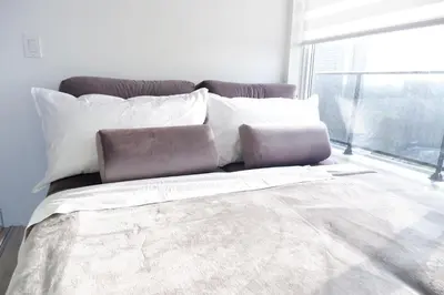 a bedroom with a bed with white pillows and a window at Modern luxury Waterfront Condo in Mississauga