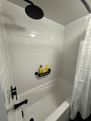 a white bathroom with a tub and a white tiled wall at Bright, Private, Peaceful Suite with Retail Conveniences Steps Away in Toronto