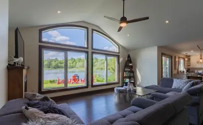 a living room with couches and a large window at Four Season Waterfront Muskoka Retreat in Bracebridge