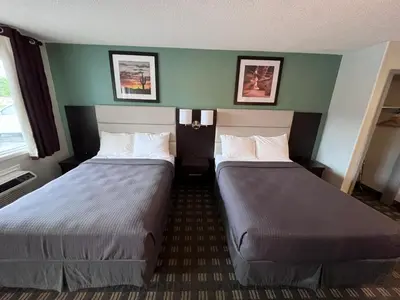 two beds in a hotel room with green walls at Wellington Inn in Bracebridge