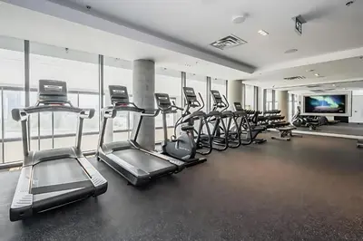 a gym with several treadmills and a row of treadms at 1BR Modern Condo - King Bed and Stunning City View in Kitchener
