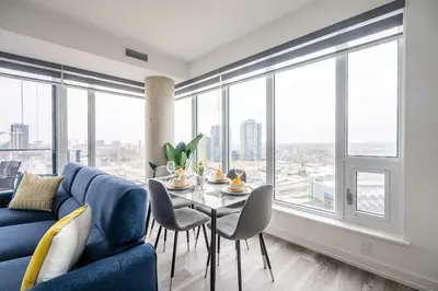 a living room with a blue couch and a table with chairs at 1BR Modern Condo - King Bed and Stunning City View in Kitchener