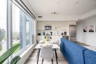 a living room with a table and a blue couch at 1BR Modern Condo - King Bed and Stunning City View in Kitchener