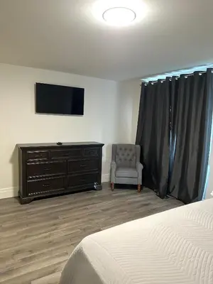 a bedroom with a bed and a tv and a chair at Stylish House W a Media Room Near Downtown Picton in Picton