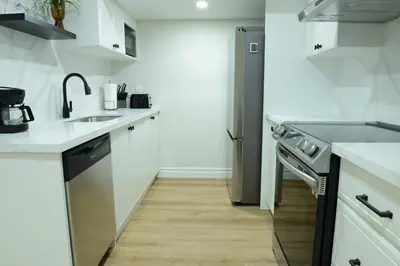 a white kitchen with a sink and a refrigerator at Spacious 2-Bed-Room near Yonge & Major Mackenzie in Richmond Hill