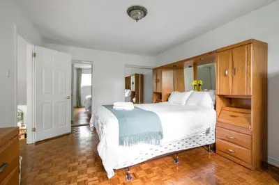 a bedroom with a large white bed and wooden cabinets at Glengarry Haus Spacious 2BR Home Away From Home in Mississauga