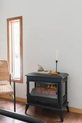 a black fireplace in a living room with a chair at The Doma Lodge - Cozy Muskoka Cabin in the Woods in Huntsville