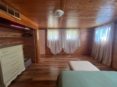 a bedroom with a bed and two windows in a cabin at Cottage in Crystal Beach in Fort Erie