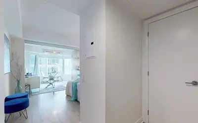 a white hallway with a blue chair and a room at University of Toronto UTSG Suites in Toronto