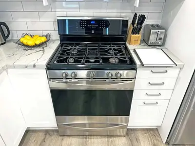 a stove top oven in a kitchen with white cabinets at Hamilton Haven - Smart Tech and BBQ Oasis - Pool in Hamilton