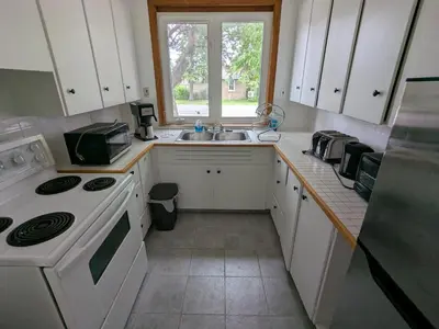 a kitchen with white cabinets and a sink and a window at Mariner motor hotel in Collingwood