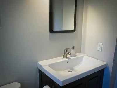 a bathroom with a white sink and a mirror at Blue Mountain 6BR Chalet Modern Hot Tub Mountain Views Walk to Village in Blue Mountains