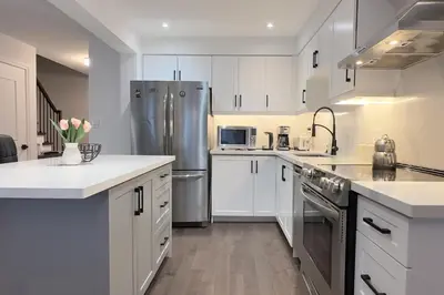 a kitchen with white cabinets and a stainless steel refrigerator at Stylish Home in Prime Location North of Toronto in Richmond Hill