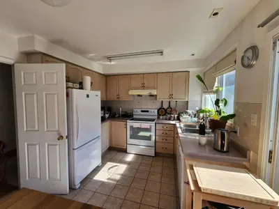 a kitchen with a white refrigerator and wooden cabinets at Scarborough Townhouse in Toronto