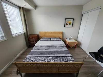 a bedroom with a bed in a room with two windows at Scarborough Townhouse in Toronto