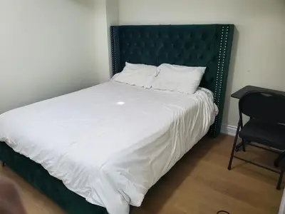 a bedroom with a bed with a black headboard and a chair at RAESABU GUEST HOUSE in Brampton
