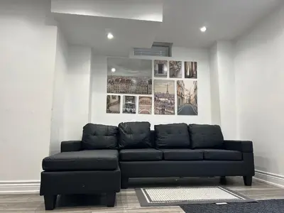 a black couch in a living room with pictures on the wall at Spacious 5BR Home for Families & Business Travelers in Ajax