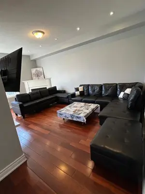a living room with a black couch and a table at Spacious 5BR Home for Families & Business Travelers in Ajax