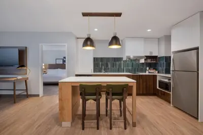 a kitchen with a table and two green chairs at Staybridge Suites Port Elgin by IHG in Port Elgin
