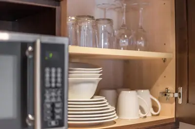 a kitchen cabinet with plates and cups and a microwave at Country Club Charm - 4-Bed Radiant Resort Condo in Edgar
