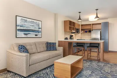 a living room with a couch and a kitchen at Candlewood Suites Collingwood by IHG in Collingwood