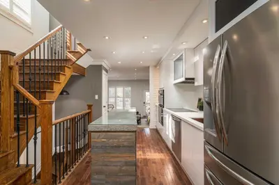 a kitchen with a staircase and a stainless steel refrigerator at Beautiful 3BR House in the Heart of Greek Town in Toronto