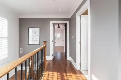 a staircase in a home with white walls and wood floors at Beautiful 3BR House in the Heart of Greek Town in Toronto