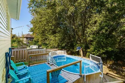a swimming pool with two blue chairs next to a fence at Fun & Cozy Retreat: Nature & Games in Trenton