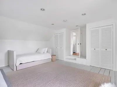 a bedroom with white walls and a bed with a rug at The Gem - Beautiful farmhouse with hot tub in West Lake