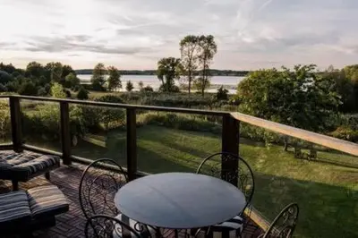 a balcony with a table and chairs and a view of a lake at Away in the County-Sandbanks Pec in Cherry Valley