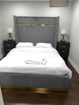 a bed with a metal headboard and two night stands at Tosam Luxury Lodge Two Bedroom Suite in Brampton