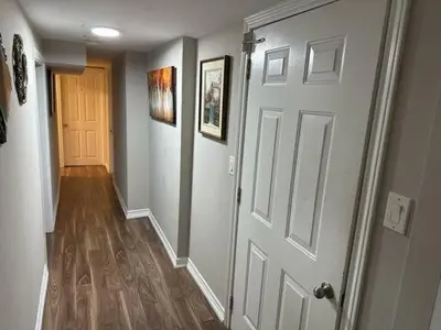 a hallway with a white door and a wooden floor at Affordable stay near the OPG TV and parking in Pickering