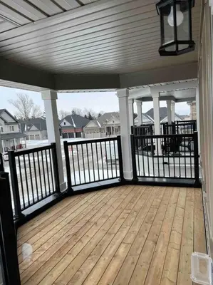 a porch with a wooden deck with black railing at Modern & Cozy Kawartha Getaway in Kawartha Lakes