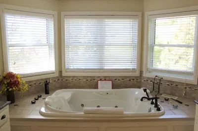 a white bath tub in a bathroom with three windows at Norfolk Guest House Inn in Guelph