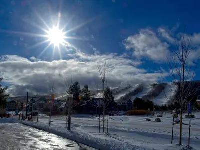 a sun shining in the sky over a snow covered field at Modern Townhome at Wintergreen Sauna Steps from Blue Mountain Village in Blue Mountains