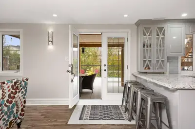 a kitchen with white cabinets and a counter with stools at Walk-out Basement Apartment with Private Entrance in Brampton