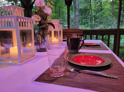 a table with a purple table cloth with candles and a glass at Anthropocene Jewel Cottage in Milton
