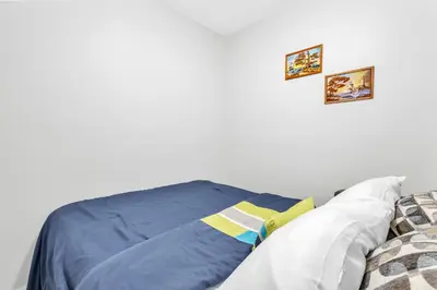 a bed with a blue blanket and two pictures on the wall at Modern 1 Bedroom + Den in Cambridge in Cambridge