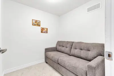 a couch in a living room with white walls at Modern 1 Bedroom + Den in Cambridge in Cambridge