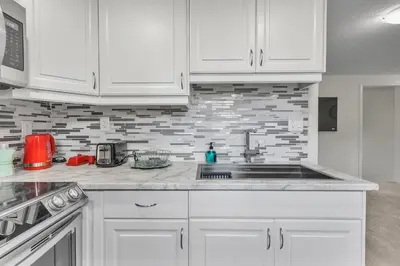 a kitchen with white cabinets and a sink at Modern 1 Bedroom + Den in Cambridge in Cambridge
