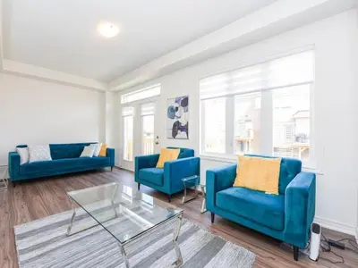 a living room with two blue chairs and a glass table at Stylish Home in Waterdown in Hamilton